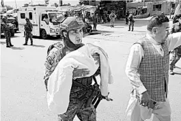  ?? RAHMAT GUL/AP ?? A security officer carries a baby Tuesday after an attack on a clinic in Kabul, Afghanista­n.