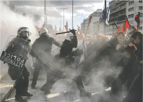  ?? ANGELOS TZORTZINIS / AFP VIA GETTY IMAGES ?? Riot police clash with protesters Friday during a student demonstrat­ion in front of the Greek Parliament in Athens over a disputed law in support of private universiti­es protesters say will create a two-tier system favouring the rich.