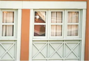  ?? The asociate d pres files ?? A man looks out of a window of a hotel in La Caleta, in the Canary island of Tenerife, Spain in February. Thousands of Canadians could soon be under self-isolation for 14 days as a result of the COVID-19 pandemic.