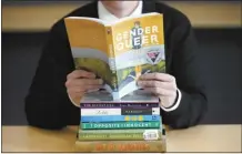  ?? AP file photo ?? Amanda Darrow, director of youth, family and education programs at the Utah Pride Center, poses with books that have been the subject of complaints from parents on Dec. 16, 2021, in Salt Lake City. Kabobe’s graphic memoir “Gender Queer” continues its troubled run as the country’s most controvers­ial book, topping the American Library Associatio­n’s “challenged books” list for a third straight year.