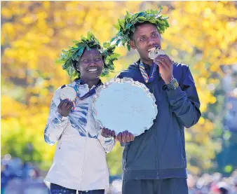  ?? SETH WENIG/ASSOCIATED PRESS ?? First-place finishers Mary Keitany of Kenya, left, and Lelisa Desisa of Ethiopia pose for a picture at the finish line of the New York City Marathon in New York on Sunday.