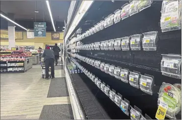  ?? PARKER PURIFOY — THE ASSOCIATED PRESS ?? Shoppers walk past empty aisles of produce at a Safeway grocery store. Shortages at U.S. grocery stores have grown in recent weeks as new problems — like the fast-spreading omicron variant and severe weather — have plagued retailers.