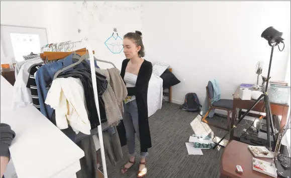  ?? Matthew Brown / Hearst Connecticu­t Media ?? Annika Moberg, of Sherman, sorts through a clothes rack in her apartment in the University of Connecticu­t residence hall at 900 Washington Blvd., in downtown Stamford.