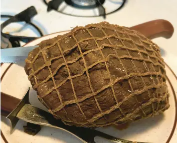  ?? FILE ?? A string netting trusses a traditiona­l beef rump roast, shown here ready to cool slightly and carve into slices of roast beef after removed from the farm oven by the mother of columnist Phil Potempa.