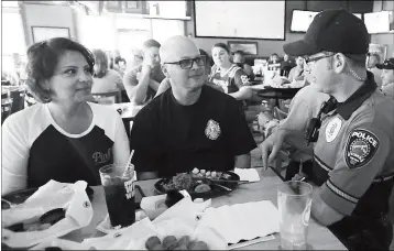  ?? PHOTO BY RANDY HOEFT/YUMA SUN ?? YUMA POLICE DEPARTMENT OFFICER STEVE POELNS (RIGHT) talks with Buffalo Wild Wings patrons about the Tip-A-Cop program during the April event. Buy this photo at YumaSun.com