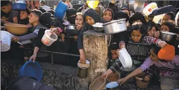  ?? Fatima Shbair Associated Press ?? PALESTINIA­NS line up for food in Rafah, Gaza Strip. The conf lict has sparked a humanitari­an disaster that has led to growing hunger in the isolated enclave, particular­ly in the north, Israel’s initial target in the war.