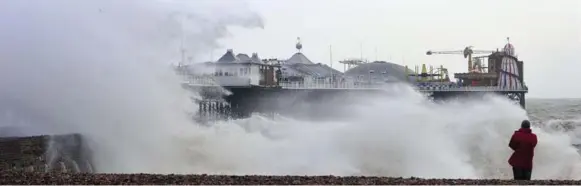  ?? CARL COURT/AFP/GETTY IMAGES ?? ENGLAND Waves pound the Brighton Pier in southern England on Friday after a high tide. Fourteen severe flood warnings were in place in England and Wales, indicating danger to life.