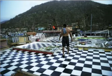  ?? THE ASSOCIATED PRESS ?? Nestor Serrano walks on the upstairs floor of his home, where the walls were blown off, in the aftermath of Hurricane Maria, in Yabucoa, Puerto Rico. Maria has thrown Puerto Rico’s already messy economic recovery plans into disarray.