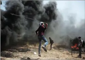  ?? The Associated Press ?? A Palestinia­n protester hurls stones at Israeli troops during a protest at the Gaza Strip’s border with Israel, Friday.