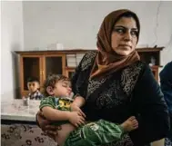  ??  ?? A volunteer social worker holds an infant boy who was rescued from the rubble in the Old City of Mosul.