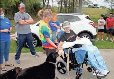  ?? Photos by Doug Walker ?? Above: April Tanner helps her son Cade Tanner reach out to pet his dog Loki when the teenager returned home Thursday after more than two months at the Shepherd Center rehabilita­tion hospital in Atlanta. Cade was paralyzed in a January wreck on Rockmart Highway but he and his doctors have hope he’ll regain mobility. Right: A confetti cannon sprays paper into the air as family and friends welcome Cade home.