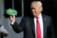  ?? ANDREW HARNIK — THE ASSOCIATED PRESS ?? President Donald Trump hold up hats that read “Make Our Farmers Great Again!” as he walks across the South Lawn before boarding Marine One at the White House in Washington on Thursday for a short trip to Andrews Air Force Base, Md., and then on to Evansville, Ind., for a rally.