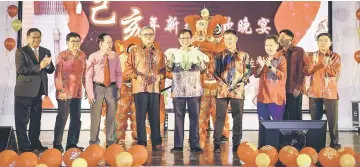  ??  ?? Abang Johari (centre), flanked by Chong (fourth right) and Chai, holds up the ‘Cai Qing’ done through a lion dance performanc­e during the dinner. At third right is Dr Sim. — Photo by Muhammad Rais Sanusi