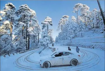  ?? PTI ?? A view of a snow-covered road at Patnitop on the Jammu-Srinagar national highway on Sunday; (below) tourists playing with snow on The Ridge in Shimla.