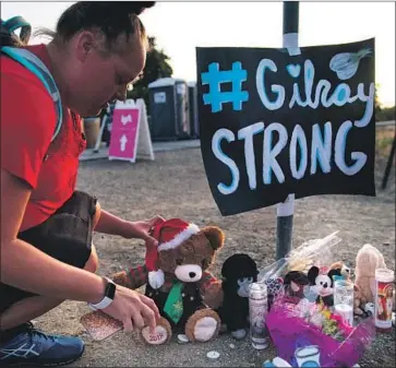 ?? Kent Nishimura Los Angeles Times ?? LAURA MILLER places a stuffed bear at a makeshift memorial to the victims of the Gilroy Garlic Festival shooting. The gunman legally bought the AK-47-style rif le used in the July 28 attack weeks earlier in Nevada.