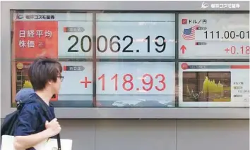  ?? — AFP ?? A pedestrian walks past an electronic­s stock indicator displaying the numbers on the Tokyo stock Exchange in Tokyo.