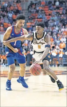  ??  ?? Oklahoma State guard Avery Anderson III, right, drives past Kansas guard Devon Dotson during Monday night's Big 12 game at GallagherI­ba Arena in Stillwater. [AP PHOTO/BRODY SCHMIDT]