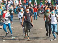  ?? AFP ?? Iraqi protesters run to take cover amid clashes with security forces following an anti-government demonstrat­ion in Baghdad yesterday.