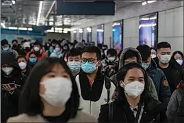  ?? ANDY WONG / AP ?? Masked commuters walk through a walkway in between two subway stations as they head to work during the morning rush hour in Beijing on Tuesday. China continues to adapt to an easing of strict virus containmen­t regulation­s.