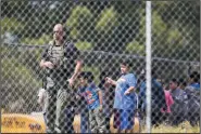  ?? GINA FERAZZI/LOS ANGELES TIMES ?? A SWAT officer stands guard with evacuated children on the playground after a shooting inside North Park Elementary School on Monday in San Bernardino.