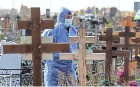  ?? AP ?? A grave digger wearing a protective suit observes during a COVID-19 victim burial outside of a cemetery outside in Omsk, Russia, on Thursday.