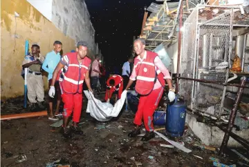  ??  ?? Rescue workers carry a body of a man killed in a car bomb attack in front of a restaurant at the Maka al Mukaram street in Mogadishu, Somalia . — Reuters photo