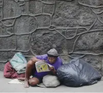  ?? (Ricardo Moraes/Reuters) ?? A HOMELESS WOMAN reads a newspaper on a street in Rio de Janeiro.