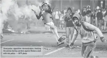  ??  ?? Venezuelan opposition demonstrat­ors blocking the avenue during a protest against Maduro clash with riot police. — AFP photo