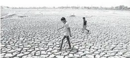  ?? AJIT SOLANKI/AP 2016 ?? Boys walk through a dried patch of Chandola Lake in Ahmedabad, India. The 2010s averaged 58.4 degrees worldwide, or 1.4 degrees higher than the 20th century average.