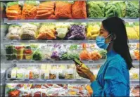  ?? WEI PEIQUAN / XINHUA ?? A visitor walks past a booth of ready-to-eat meals during an expo in Fuzhou, Fujian province.