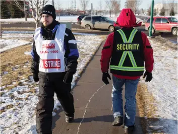  ?? LIAM RICHARDS ?? A striking Co-op employee walks past a security staff member on the picket line at a gas and food store in Saskatoon Wednesday. The union is calling for an investigat­ion into guards’ alleged misconduct.