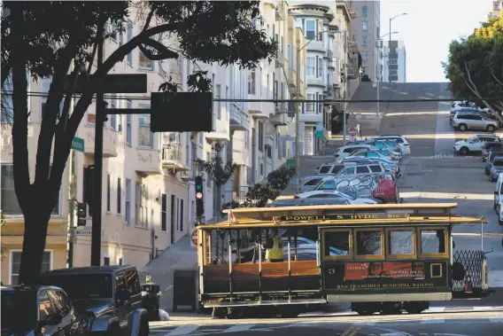  ?? Photos by Jessica Christian / The Chronicle ?? A cable car leaves the barn at Mason and Powell streets to pick up riders. Not all of the cable cars will be resuming their usual routes immediatel­y.