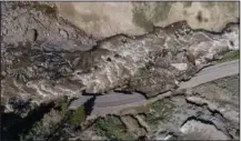  ?? ?? Receding floodwater­s flow Thursday past sections of North Entrance Road washed away at Yellowston­e National Park in Gardiner, Mont.