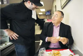  ??  ?? Delicatess­en owner Sandro Giustini visits with City of Windsor CEO Onorio Colucci as he enjoys a tuna melt named in his honour. It contains tuna, jalapeno havarti on fresh rye with heaps of spicy pickled vegetables.