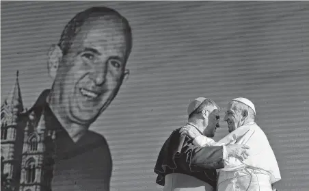  ?? Alessandra Tarantino / Associated Press ?? Pope Francis hugs archbishop of Palermo Corrado Lorefice during a rally Saturday in Piazza Politeama, in Palermo, Italy. Francis paid tribute to the Rev. Giuseppe “Pino” Puglisi (pictured in the background), who was slain by mobsters 25 years ago.