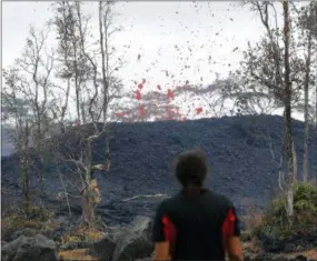  ?? MARCO GARCIA — THE ASSOCIATED PRESS ?? Abe Pedro watches lava shoot out of a fissure on Pohoiki Rd, Friday, near Pahoa, Hawaii. Hawaii residents covered their faces with masks after a volcano menacing the Big Island for weeks exploded, sending a mixture of pulverized rock, glass and crystal into the air in its strongest eruption of sandlike ash in days.