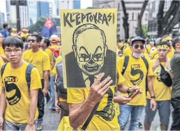  ??  ?? In this file photo from 2016, a protester holds a placard with a caricature depicting Malaysian Prime Minister Najib Razak during a mass rally calling for Razak’s resignatio­n, in Kuala Lumpur.