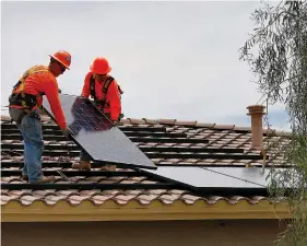  ?? The Associated Press ?? n In this July 28, 2015, file photo, electricia­ns, Adam Hall, right, and Steven Gabert install solar panels on a roof for Arizona Public Service company in Goodyear, Ariz. As states across the U.S. West beef up their renewable energy mandates, a push to do so in Arizona has been met by fierce resistance from the Republican governor and GOP-dominated Legislatur­e.