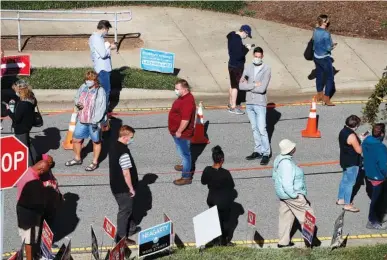  ?? ETHAN HYMAN/ THE NEWS & OBSERVER VIA AP ?? Voters wait in line outside the Herbert C. Young Community Center in Cary, N.C., on the first day of early voting Thursday. Almost 21 million American voters have already cast ballots in the 2020 presidenti­al election.