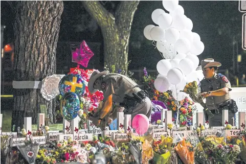  ?? AFP ?? Police officers lay flowers at a makeshift memorial outside Uvalde County Courthouse in Uvalde, Texas, on Thursday.