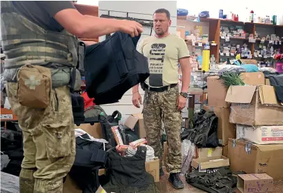  ?? GETTY IMAGES ?? Viacheslav Kovalenko, who has turned his sporting goods store in the Donetsk town of Sloviansk into a donation centre for Ukrainian soldiers, helps a soldier select new body armour. The facility, run by volunteers, has a stockpile of medication­s, food, ammunition and other supplies.