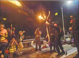  ?? Anthony Wallace AFP/Getty Images ?? A PROTESTER shoots an arrow to light a barricade at the Chinese University of Hong Kong. “We have to protect our home and our school,” one student said.