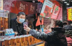  ?? AFP ?? A customer shows an Alipay payment confirmati­on to an employee at a beverage shop in Beijing.