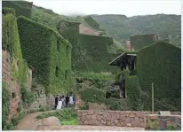  ?? FU TING/AP ?? Visitors make their way down perilous footpaths winding past structures worn down by roots, rain, vines and wind in the abandoned fishing village of Houtouwan.
