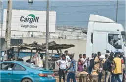  ?? ISSOUF SANOGO/GETTY-AFP ?? People in the Ivory Coast gather July 17 near a cocoa factory operated by Cargill, one of largest cocoa traders in the world, in Yopougon, a suburb of Abidjan.