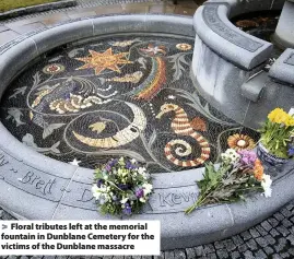  ?? Jane Barlow ?? > Floral tributes left at the memorial fountain in Dunblane Cemetery for the victims of the Dunblane massacre