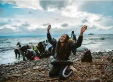  ?? Foto: Angelos Tzortzinis, dpa ?? Überschwän­glicher Dank: Diese Migranten haben es geschafft, mit dem Schlauchbo­ot auf die griechisch­e Insel Lesbos überzusetz­en.