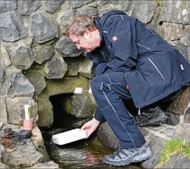  ??  ?? Quellenfor­scher Stefan Zaenker hockt an der Fulda-quelle in Gersfeld und nimmt mit einem Behältnis eine Wasserprob­e. Später wird diese dann unter einem Mikroskop untersucht und die Qualität bestimmt. Fotos: Jörn Perske