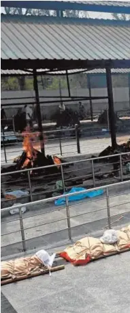  ??  ?? Un hombre pasa junto a los cuerpos de las víctimas del Covid en un campo de cremación en Nueva Delhi