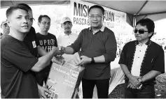  ?? - Bernama photo ?? Minister in the Prime Minister’s Department Datuk Seri Abdul Rahman Dahlan (second right) handing over a grasscutte­r machine to a respresent­ative of Kampung Linau at the Kota Belud Post-Flood Relief Mission yesterday.